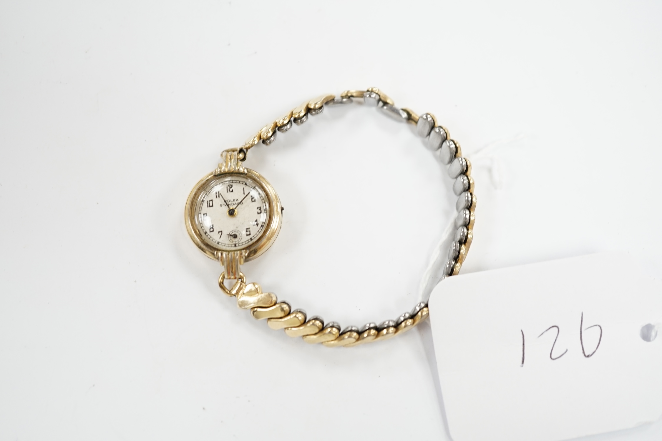 A lady's gilt metal manual wind wrist watch, the dial inscribed 'Rolex Standard', movement unsigned and no winding crown, on an associated flexible link bracelet. Condition - poor